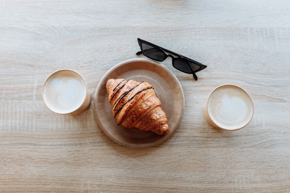close up flat lay of latte art and pastry on a rustic wooden table